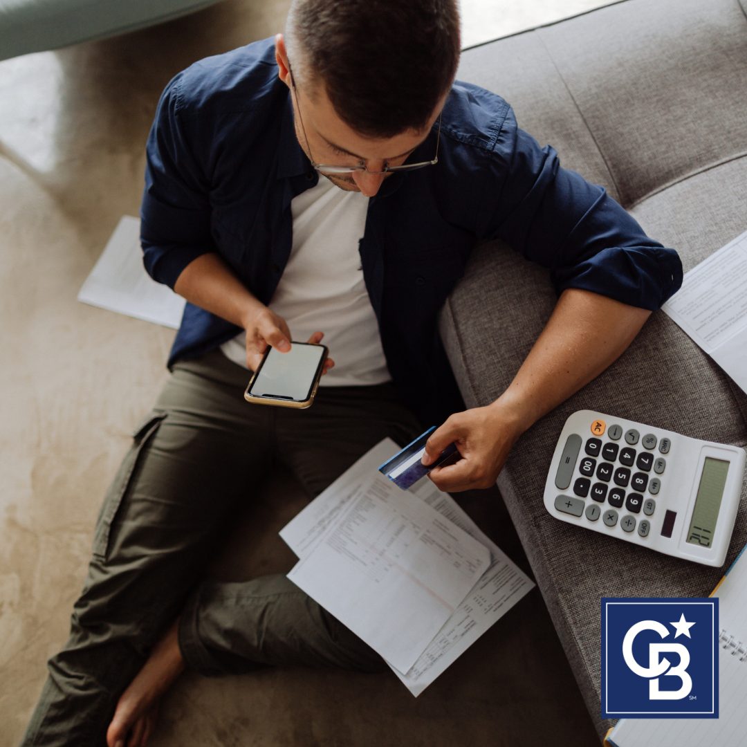 A stressed man sitting at a table with bills and paperwork symbolizing financial difficulties