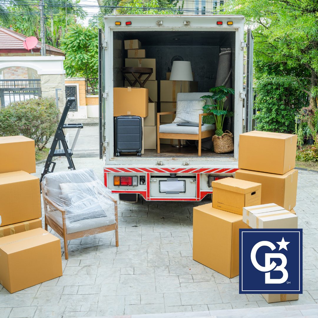 A moving truck parked in a driveway with cardboard boxes stacked nearby, ready for a home move.