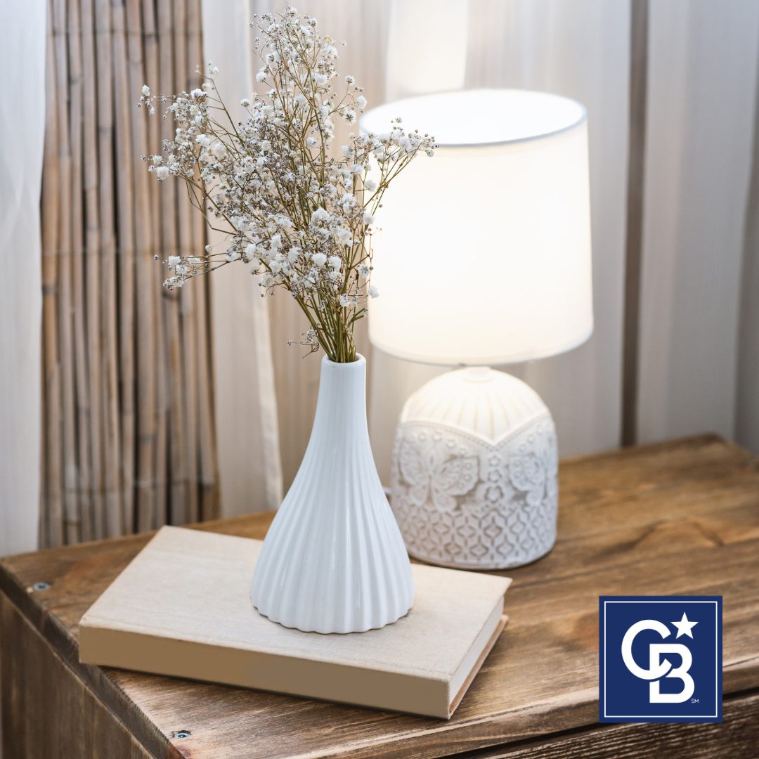 Stylish wooden table decorated with a modern lamp, an open book, and a vase of fresh flowers, reflecting 2025 home design trends.