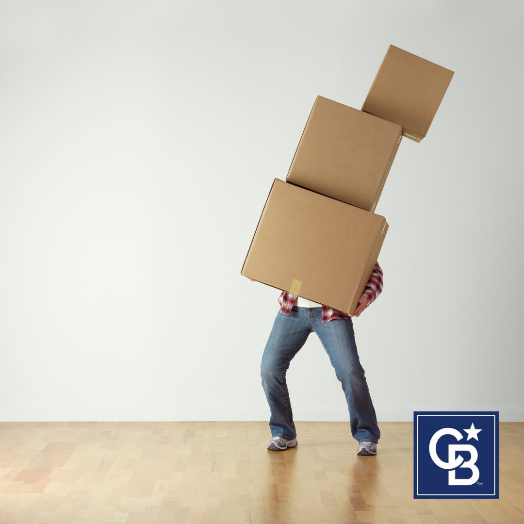 Person struggling to carry three large moving boxes, representing the challenges of packing for a move.